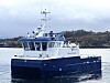 Blått og hvitt servicefartøy fra Moen Marin på stille vann nær kysten