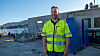 Svein Ådland i gulgrønn vernejakke foran et industriområde ved sjøen.